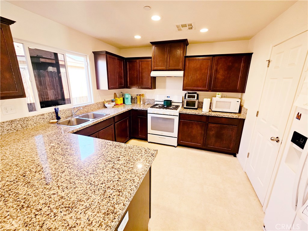 301 Moonstone Beach Court Delano, CA 93215 - Photo 5 of 31 a kitchen with stainless steel appliances granite countertop a sink stove and refrigerator