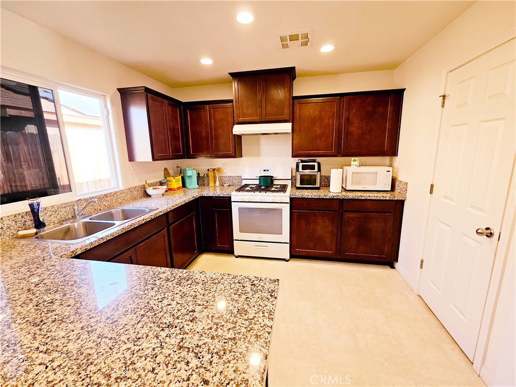 301 Moonstone Beach Court Delano, CA 93215 - Photo 10 of 31 a kitchen with stainless steel appliances granite countertop a sink stove and refrigerator