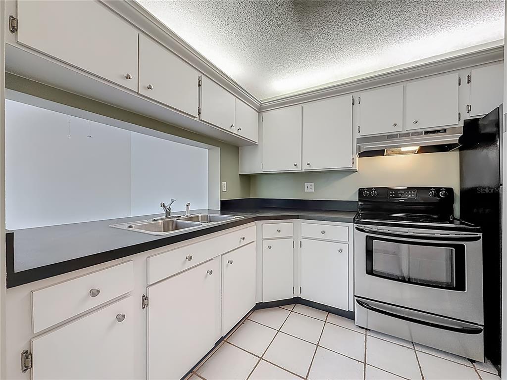 1372 Pine Ridge Circle East, Unit H3 Tarpon Springs, FL 34688 - Photo 15 of 53 a kitchen with granite countertop white cabinets stainless steel appliances and sink