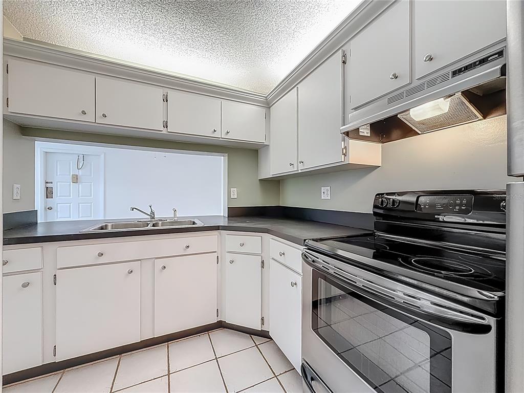 1372 Pine Ridge Circle East, Unit H3 Tarpon Springs, FL 34688 - Photo 17 of 53 a kitchen with granite countertop white cabinets and appliances