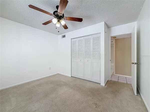 an empty room with windows and fan