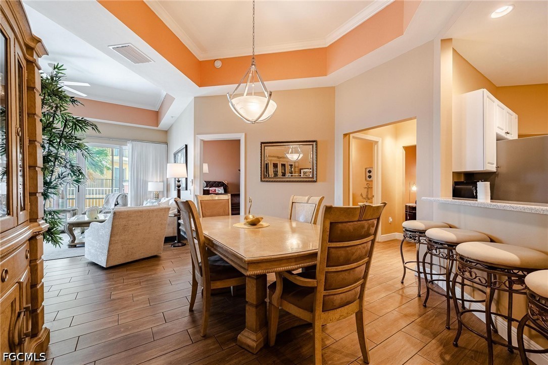 2745 First Street, Unit 306 Fort Myers, FL 33916 - Photo 15 of 50 a dining room with wooden floor a chandelier a wooden table and chairs