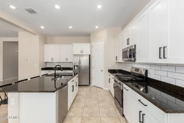 a kitchen with stainless steel appliances a table and chairs in it