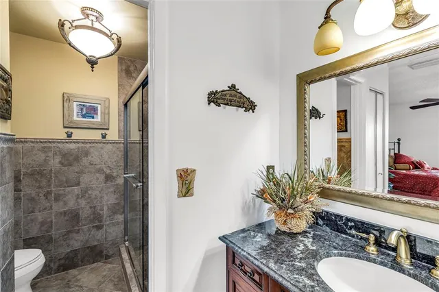 a bathroom with a granite countertop sink a toilet and mirror