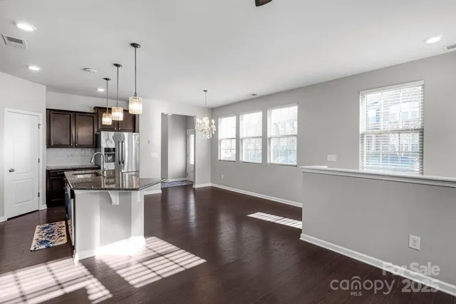 a kitchen with stainless steel appliances granite countertop a refrigerator a stove a sink dishwasher and a microwave with wooden floor