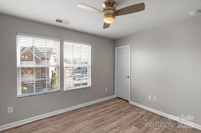 a view of an empty room with a window and wooden floor