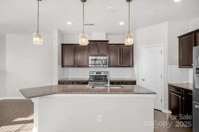 a kitchen with stainless steel appliances granite countertop a stove a sink and a refrigerator
