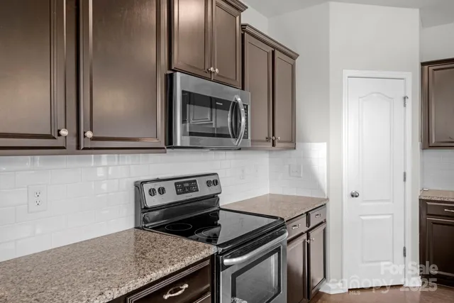 a kitchen with stainless steel appliances granite countertop a stove a microwave and a refrigerator