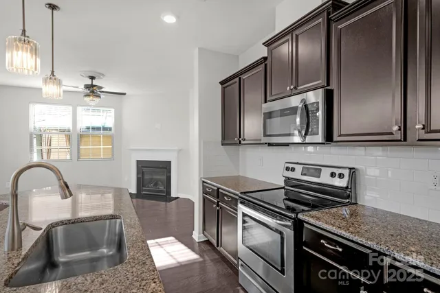 a kitchen with stainless steel appliances granite countertop a stove a sink and a microwave