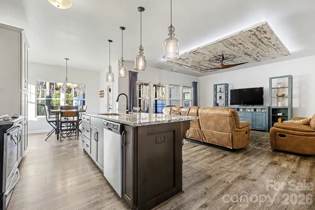 a kitchen with stainless steel appliances granite countertop a refrigerator a stove a sink a dining table and chairs
