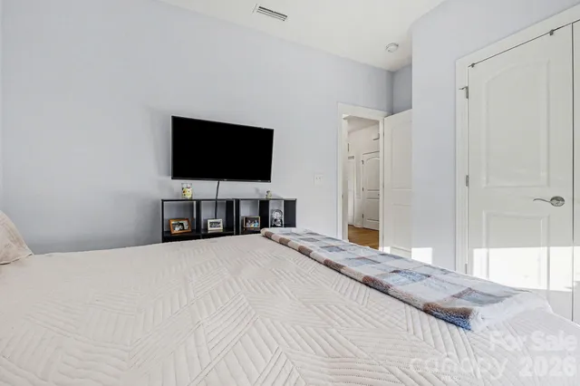 a bedroom with a bed and a flat tv screen on dresser