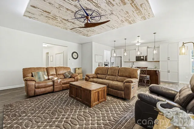 a living room with furniture a flat screen tv and a chandelier