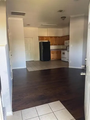 a view of a refrigerator in kitchen and an empty room