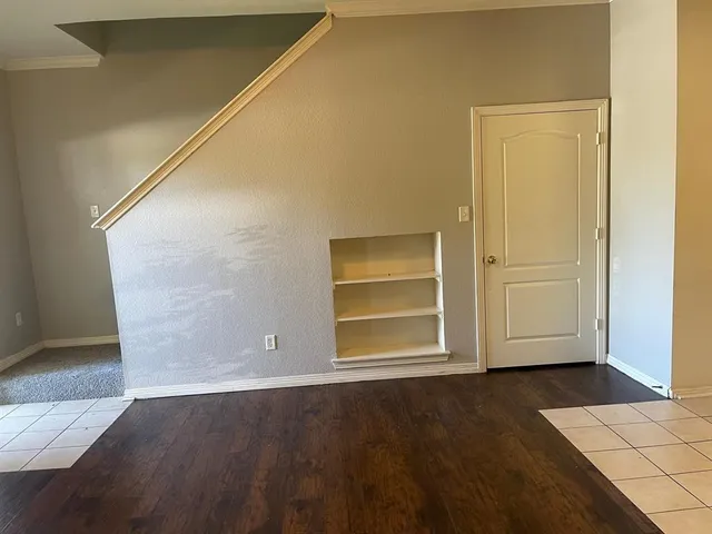 an empty room with wooden floor cabinet and windows