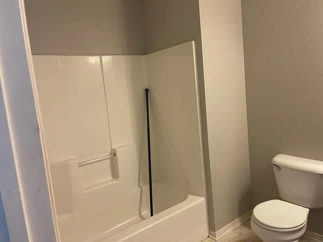 a white toilet sitting next to a bath tub
