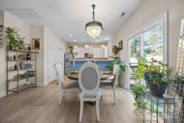 a dining room filled chandelier and kitchen view