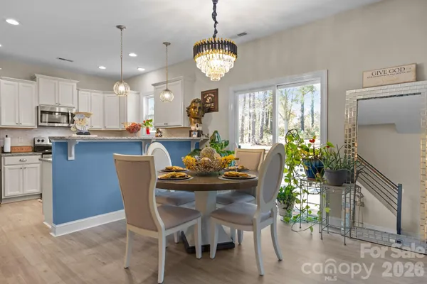 a dining room filled chandelier and kitchen view