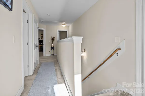 a view of a hallway with white walls and stairs