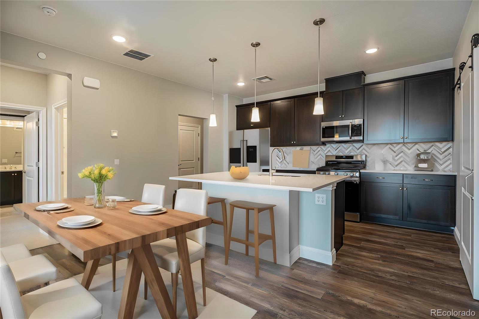 16881 Askins Loop, Unit 302 Parker, CO 80134 - Photo 2 of 11 a kitchen with a table chairs refrigerator and microwave