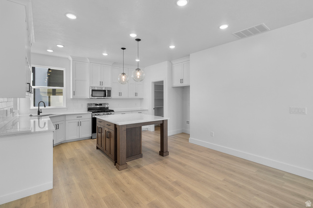 248 West 2920th Street South Logan, UT 84321 - Photo 12 of 47 Kitchen featuring white shaker cabinetry, stainless steel appliances, wood-finish flooring, a center island with pendant lighting, and recessed lighting