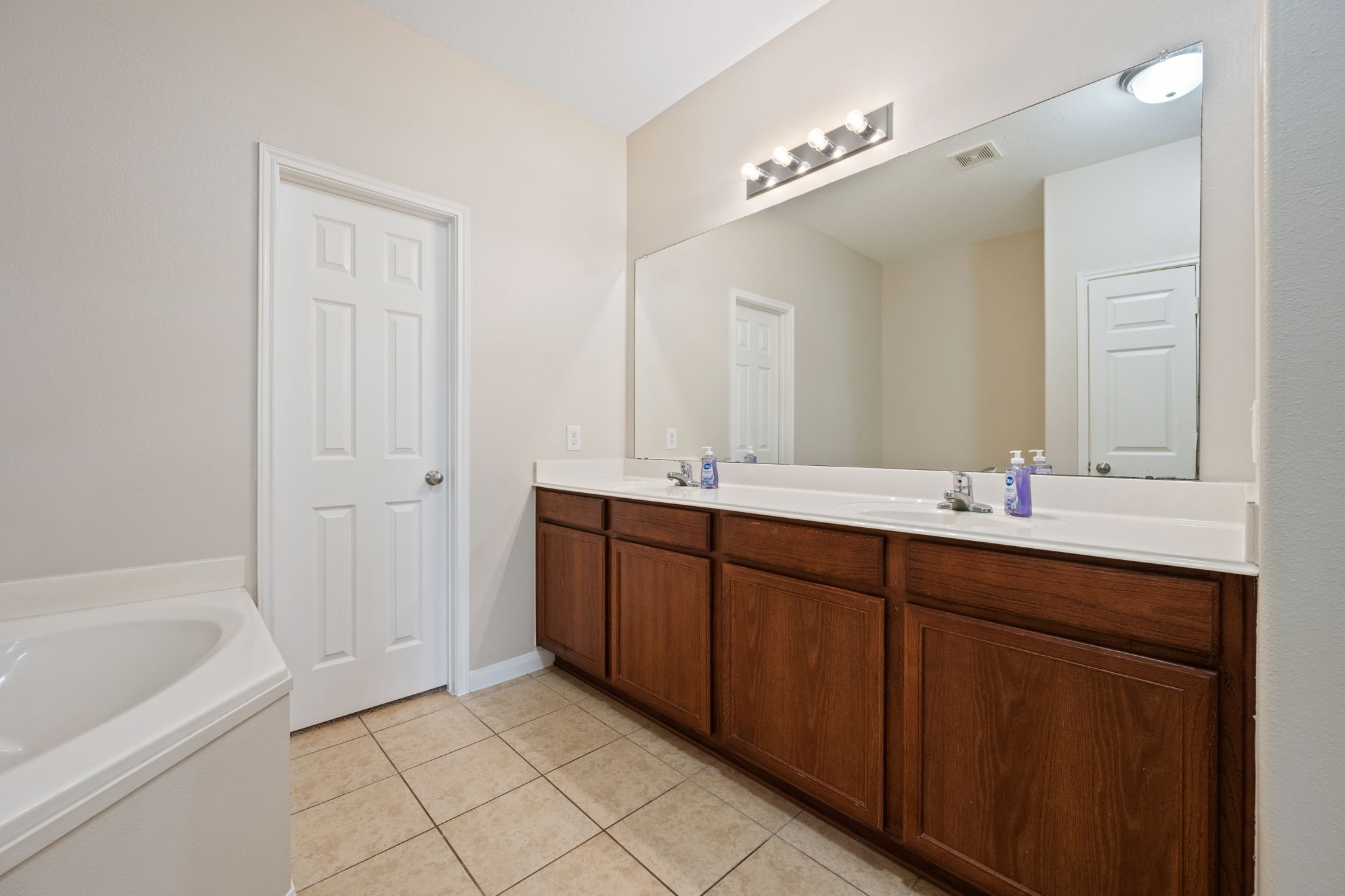 803 Marigold Road Baytown, TX 77521 - Photo 18 of 31 a bathroom with a tub a double vanity sink and mirror