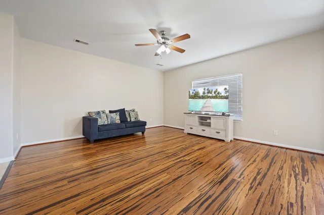 a living room with hard wood floors and a ceiling fan