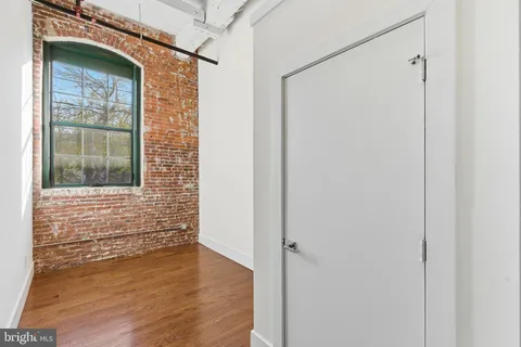 a view of an empty room with wooden floor and windows