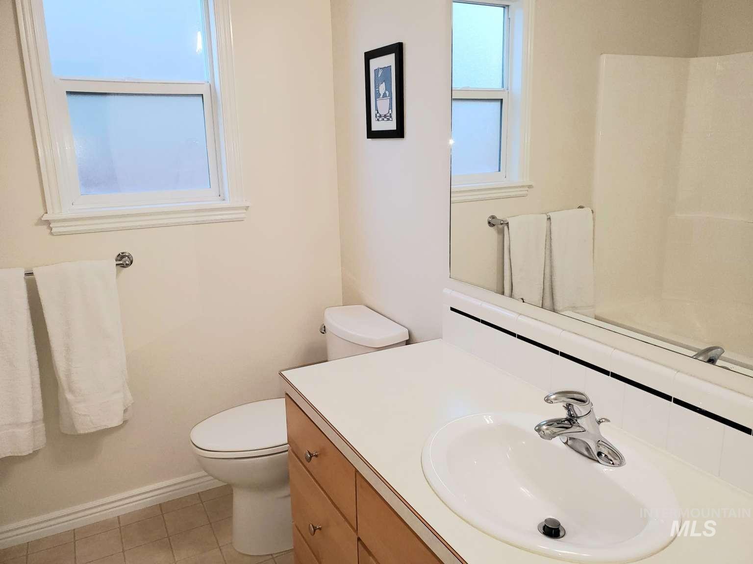 1100 East Wright Street Boise, ID 83706 - Photo 11 of 25 Bathroom featuring a light wood-finish vanity with a white countertop and integrated sink, a full-width wall mirror, and a white toilet