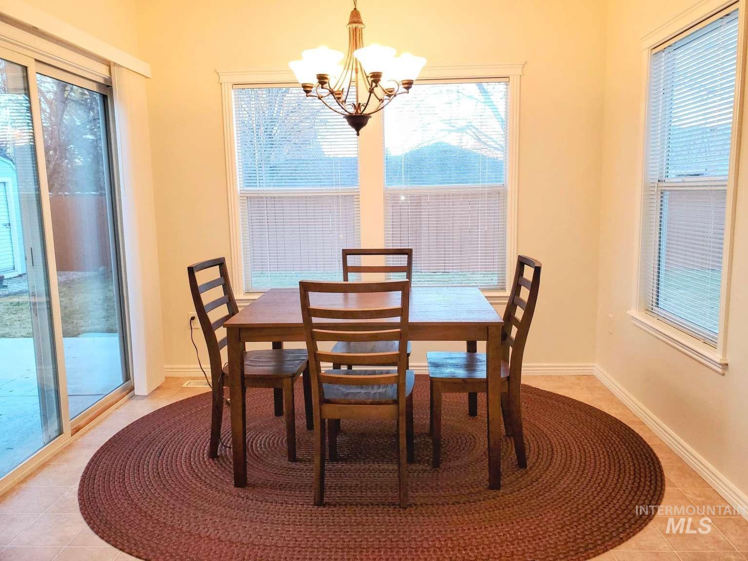 1100 East Wright Street Boise, ID 83706 - Photo 13 of 25 Dining area featuring a bronze chandelier, multiple windows with blinds, and a sliding glass door