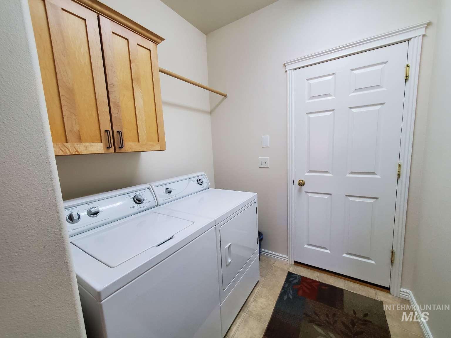 1100 East Wright Street Boise, ID 83706 - Photo 15 of 25 Laundry area featuring wood-finish cabinetry with dark hardware, a built-in hanging rod, and tile flooring