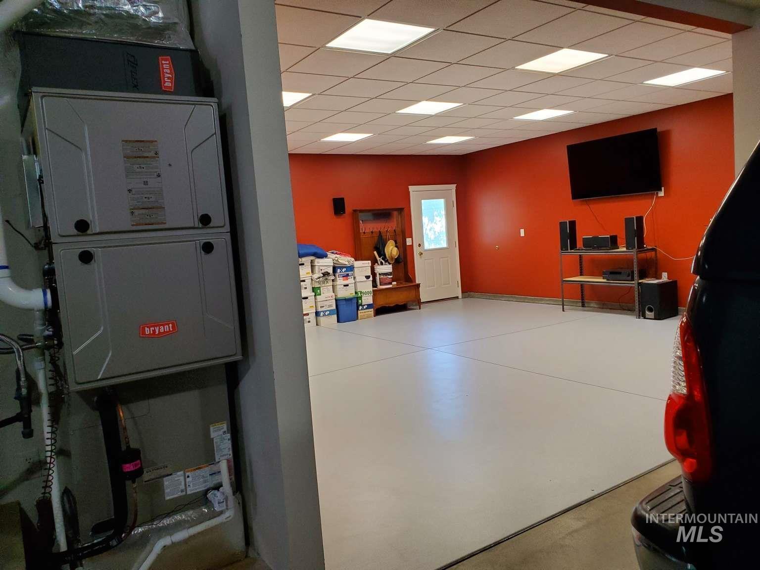 1100 East Wright Street Boise, ID 83706 - Photo 20 of 25 Spacious open room with a light gray epoxy floor and red accent walls, featuring a white exterior door