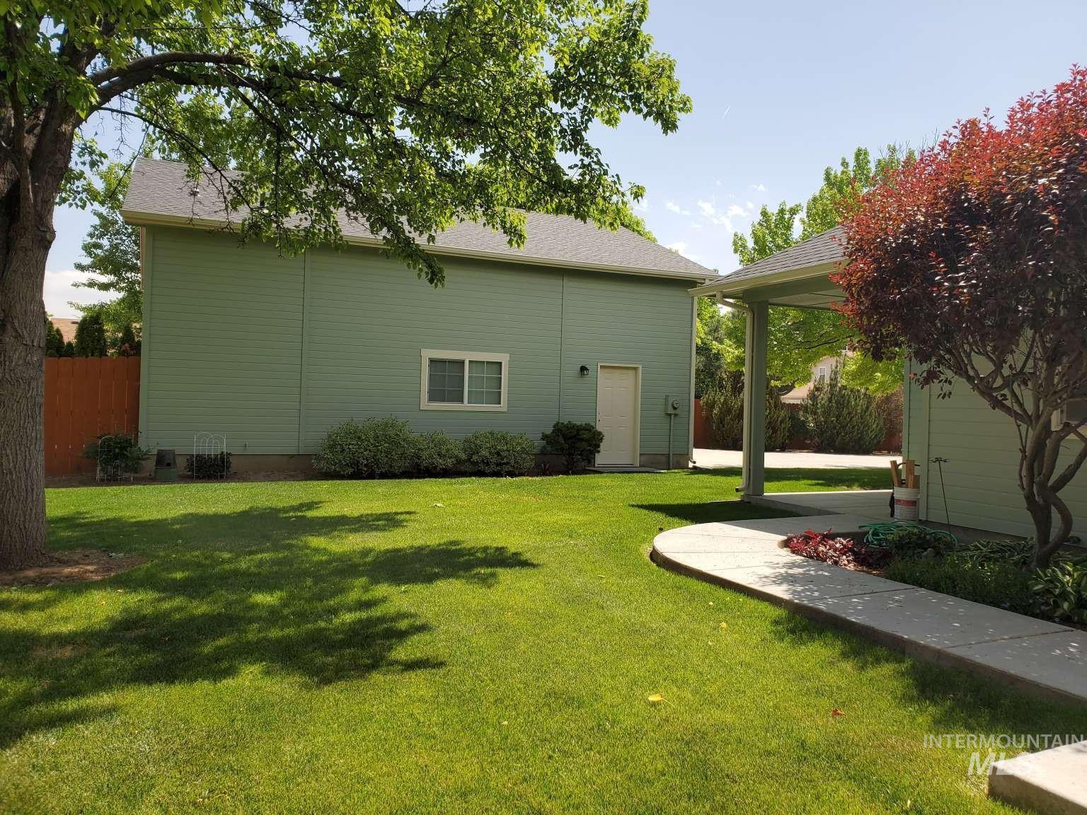 1100 East Wright Street Boise, ID 83706 - Photo 22 of 25 Expansive green lawn featuring mature trees, a curved concrete pathway, and a covered walkway connecting two structures