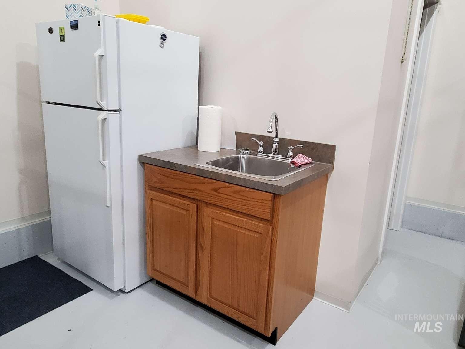 1100 East Wright Street Boise, ID 83706 - Photo 25 of 25 Kitchen featuring brown cabinetry, freestanding refrigerator, dark countertops, and concrete floors