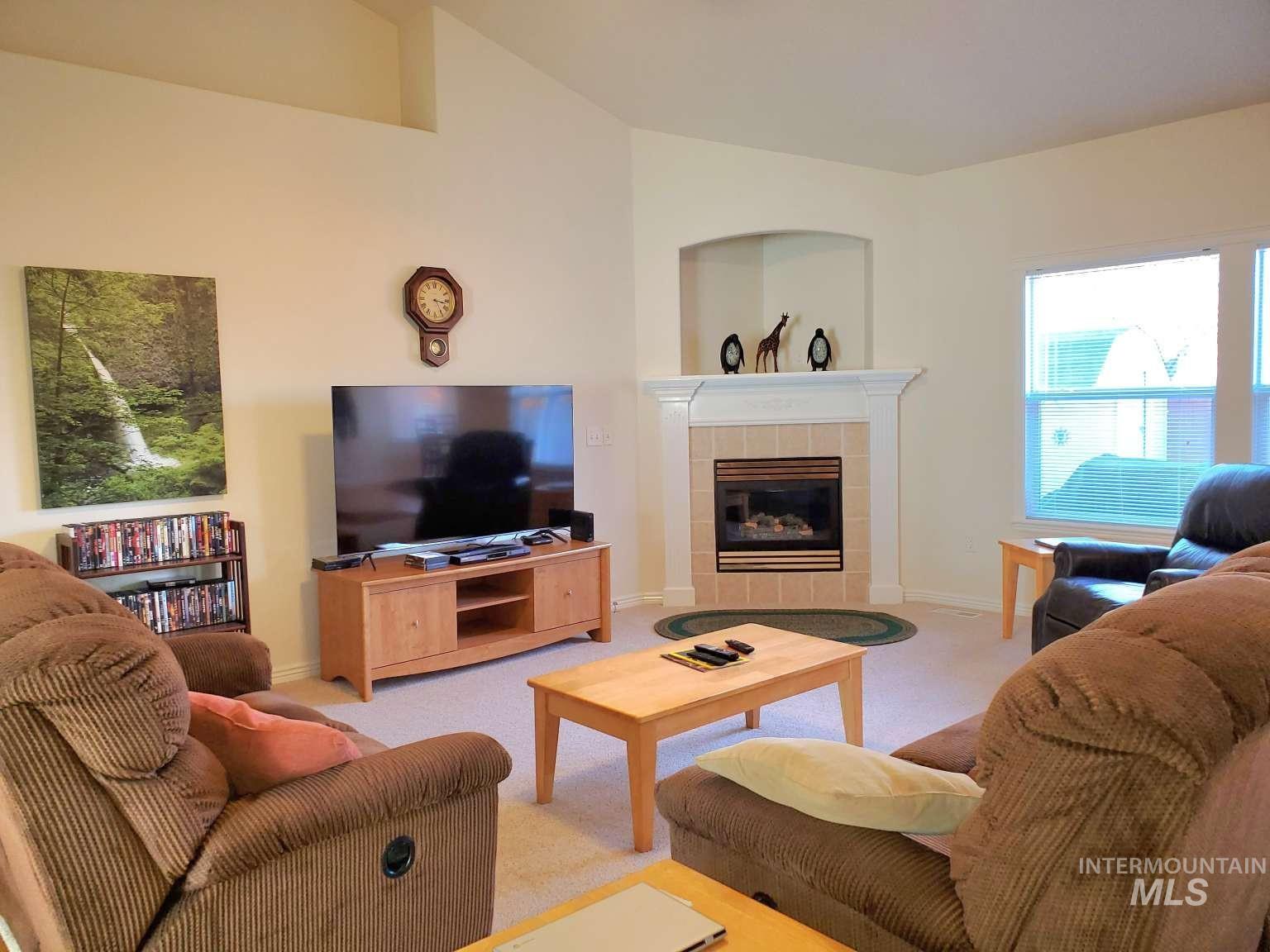 1100 East Wright Street Boise, ID 83706 - Photo 3 of 25 Living area with vaulted ceiling, a tiled fireplace, and light carpet