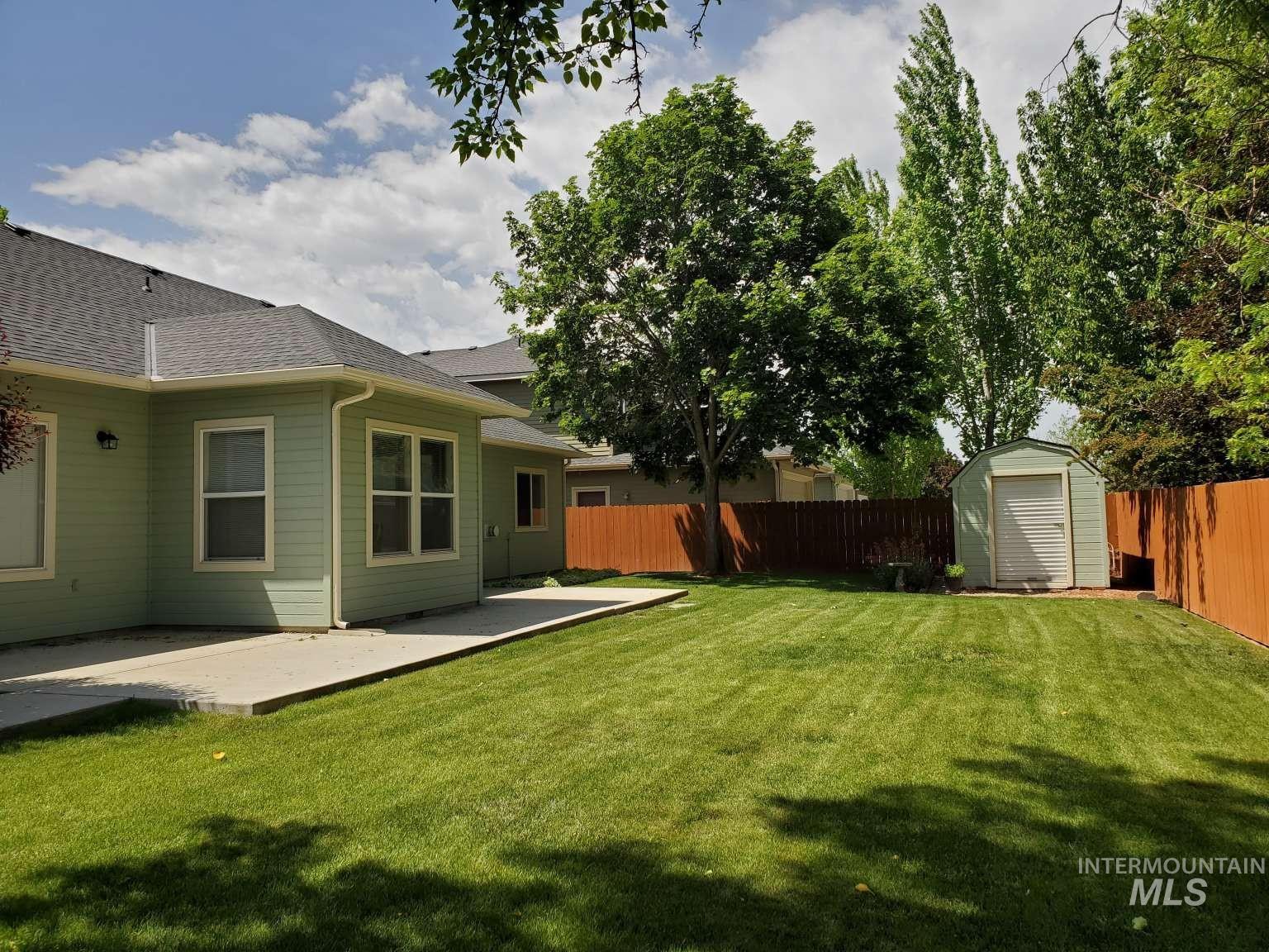 1100 East Wright Street Boise, ID 83706 - Photo 4 of 25 Expansive backyard featuring a manicured lawn, concrete patio, privacy fencing, and mature trees