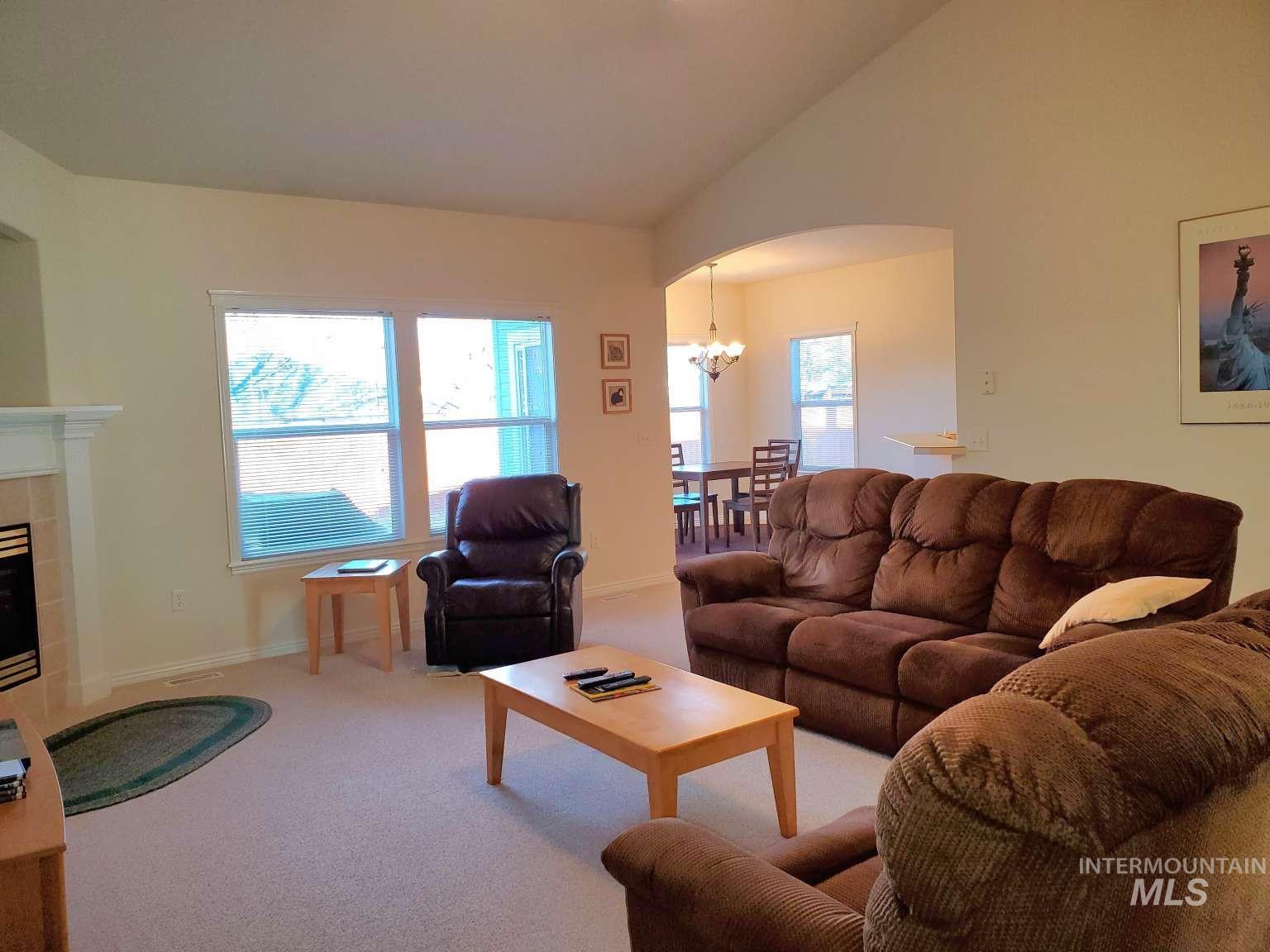1100 East Wright Street Boise, ID 83706 - Photo 4 of 25 Carpeted living area with vaulted ceiling, a chandelier, arched walkways, and a fireplace