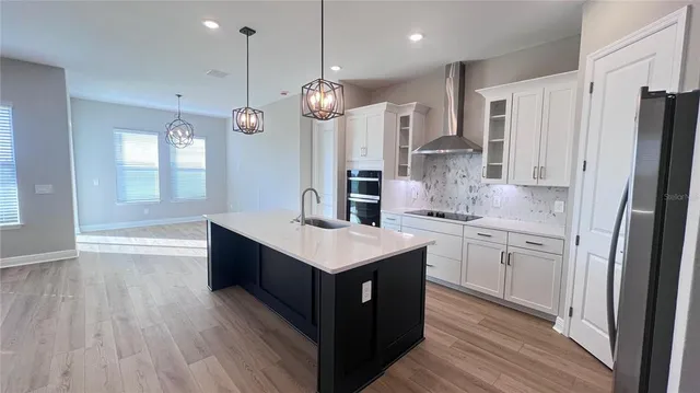 a kitchen with stainless steel appliances granite countertop a refrigerator a sink dishwasher and a stove with wooden floor