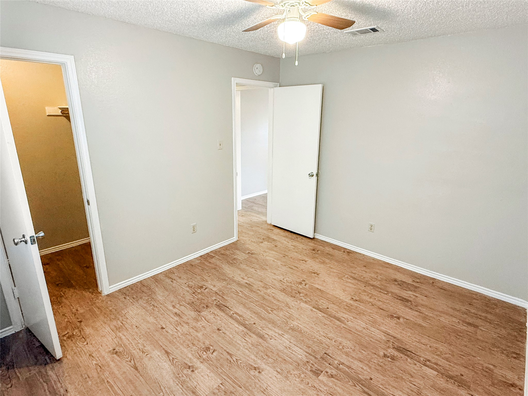 409 Rawhide Loop Round Rock, TX 78681 - Photo 7 of 14 Spacious room featuring wood-finish flooring, light gray walls, white baseboards, and a ceiling fan with integrated lighting