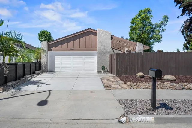 a view of a house with a small yard and a large tree