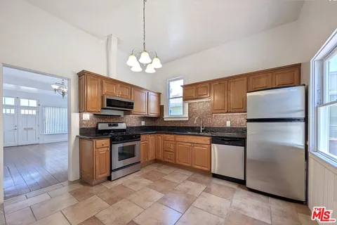 a kitchen with stainless steel appliances granite countertop a refrigerator a stove top oven a sink and dishwasher
