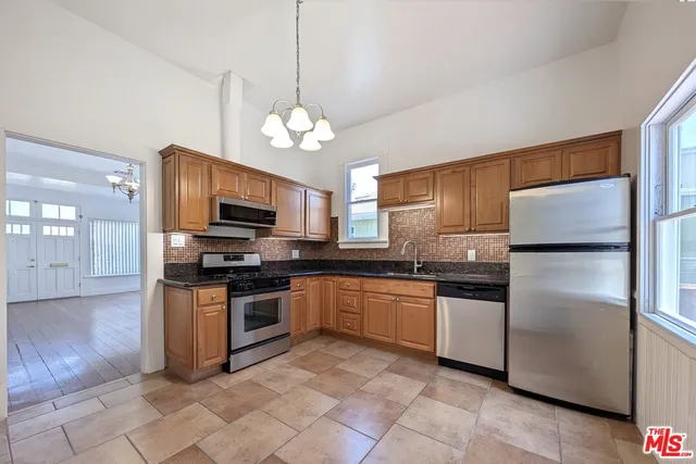 a kitchen with stainless steel appliances granite countertop a refrigerator a stove top oven a sink and dishwasher