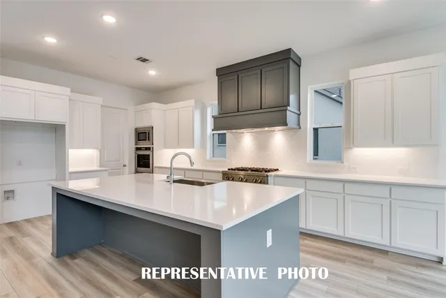 a kitchen with a sink a stove a refrigerator and white cabinets