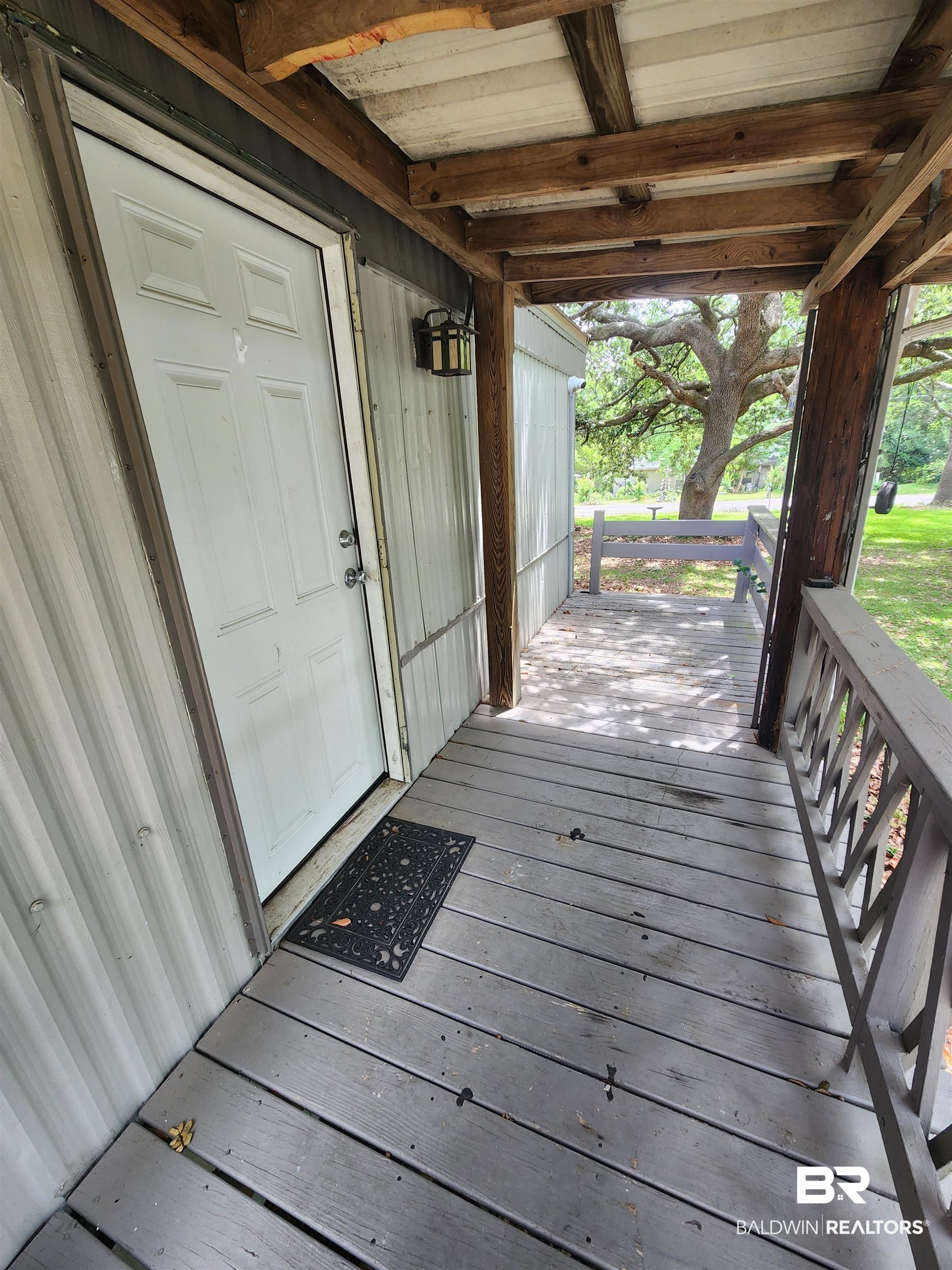 23051 Fritz Lane Foley, AL 36535 - Photo 11 of 26 Covered porch with exposed wood beams, plank flooring, and a decorative outdoor light fixture