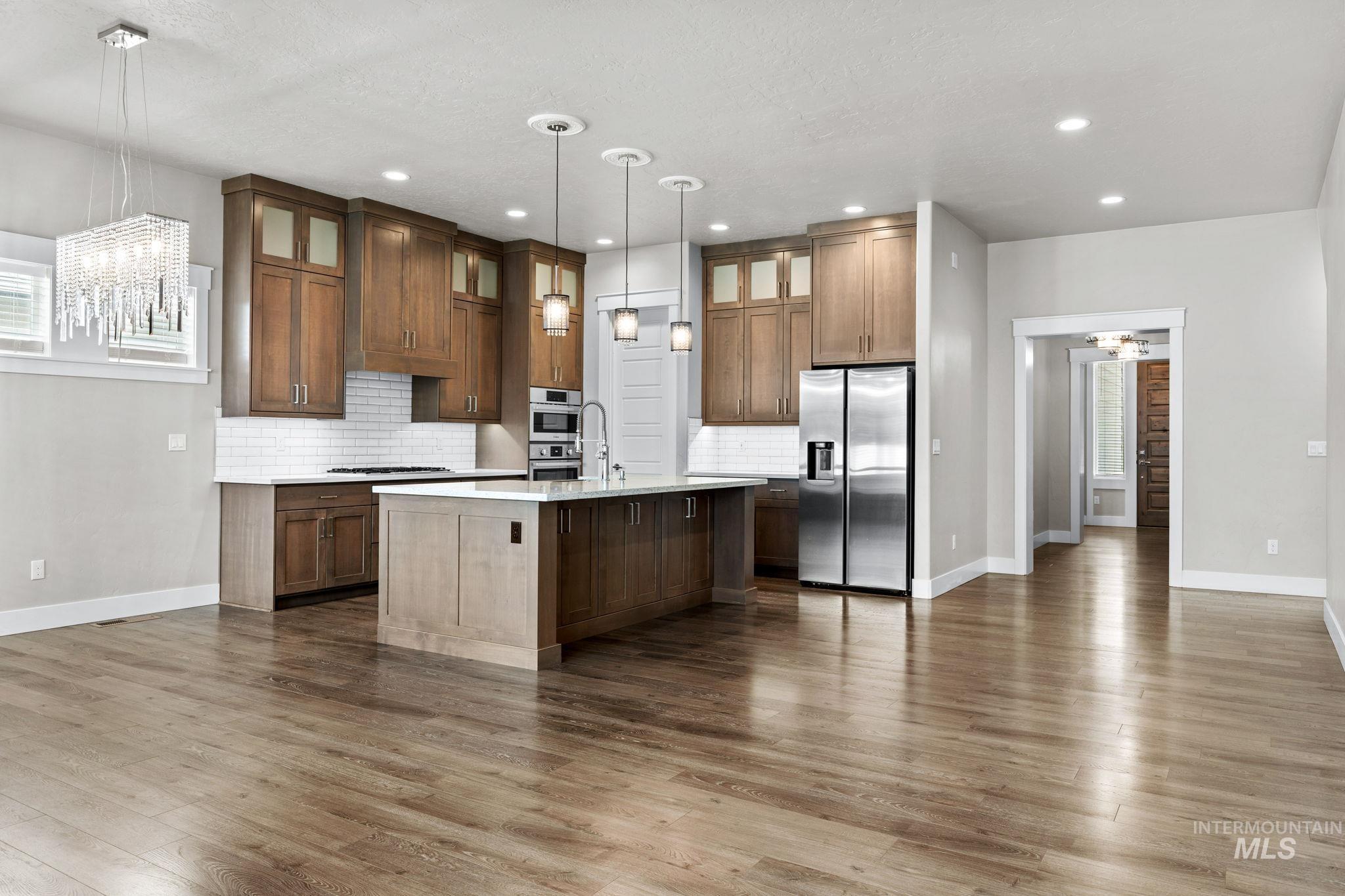 2934 East Murchison Street Meridian, ID 83642 - Photo 8 of 44 Expansive kitchen featuring wood cabinetry, stainless steel appliances, a center island with pendant lighting, and a subway tile backsplash