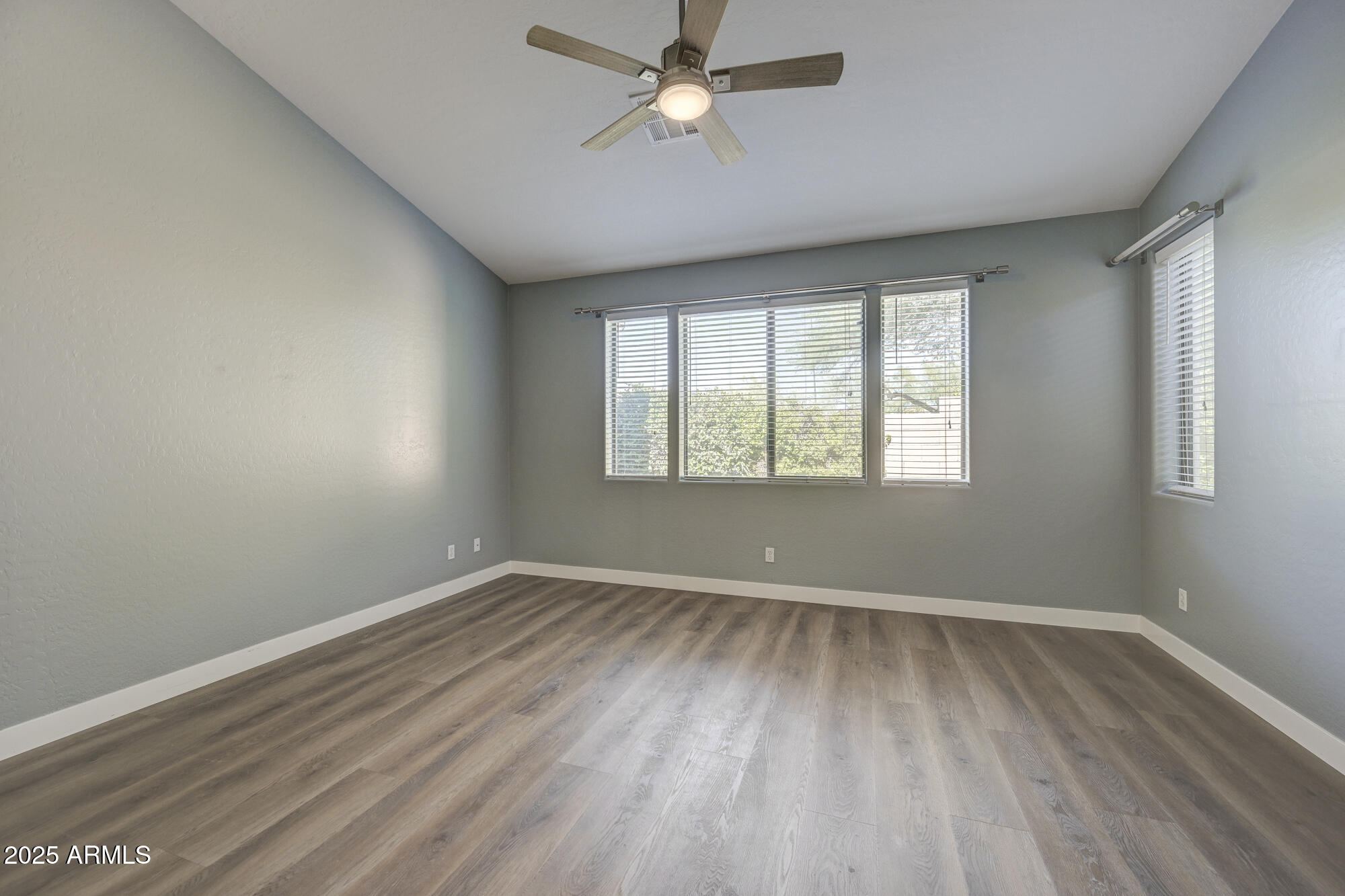 6646 East Rochelle Circle Mesa, AZ 85215 - Photo 21 of 43 an empty room with wooden floor ceiling fan and windows