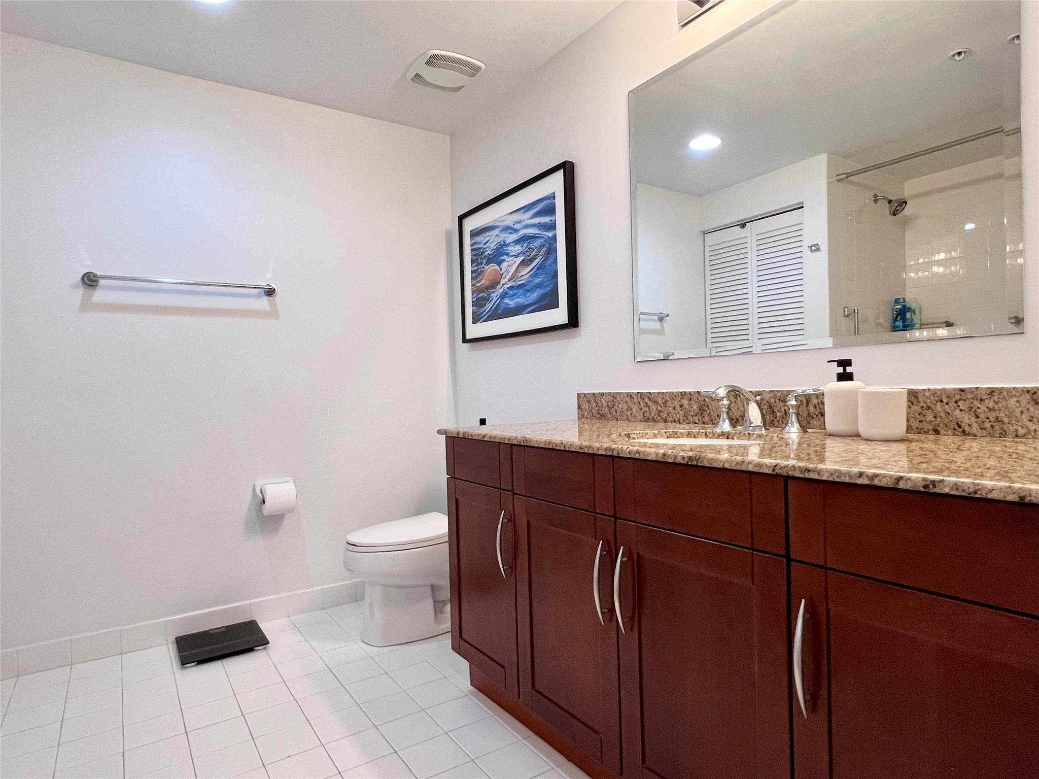 7275 Southwest 90th Way, Unit 603 Miami, FL 33156 - Photo 14 of 19 a bathroom with a granite countertop sink a toilet and a mirror
