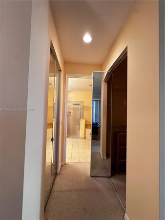 a view of a hallway with wooden floor and a bathroom