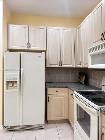 a kitchen with granite countertop white cabinets and white appliances