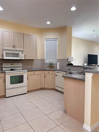 a kitchen with granite countertop white cabinets white stainless steel appliances with a sink and dishwasher