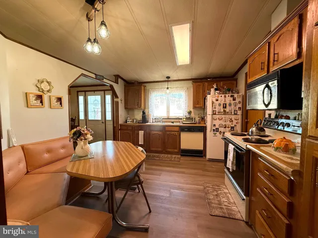 a large kitchen with stainless steel appliances kitchen island granite countertop a sink a stove a dining table and chairs with wooden floor